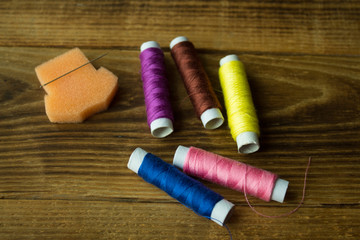 sewing thread and needle on a wooden background
