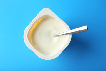 Plastic cup with yummy yogurt on color background