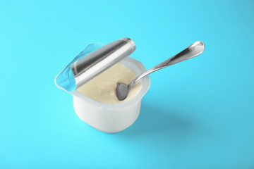 Plastic cup with yummy yogurt on color background