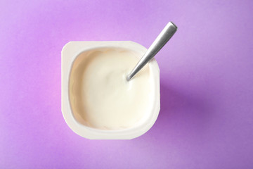Plastic cup with yummy yogurt on color background