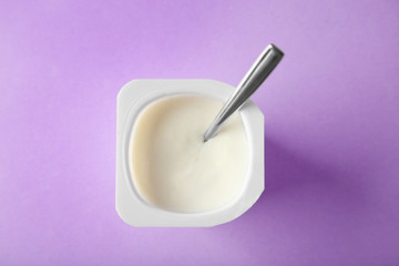 Plastic cup with yummy yogurt on color background