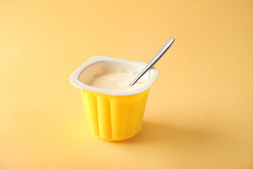 Plastic cup with yummy yogurt on color background