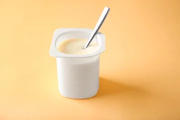 Foto auf Glas Plastic cup with yummy yogurt on color background © Africa Studio