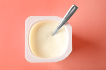 Plastic cup with yummy yogurt on color background