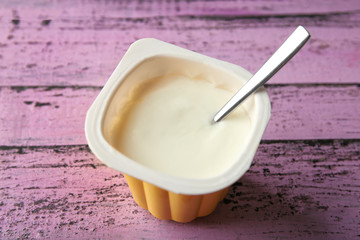 Plastic cup with yummy yogurt on color wooden background