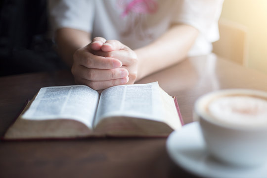 woman hands on bible. she is reading and praying over bible over wooden table