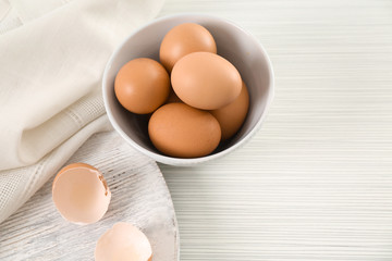 Bowl with chicken eggs on table