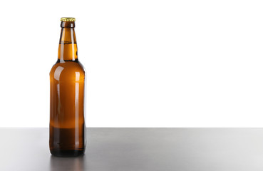 Glass bottle of beer on table against white background