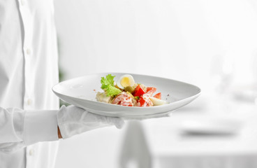 Waiter holding plate with salad, closeup