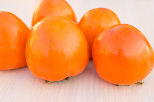 Five ripe persimmons on the wooden table