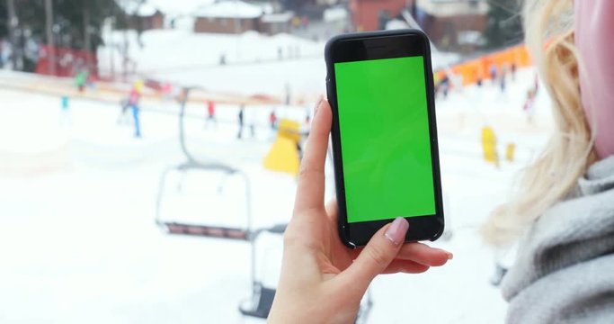 closeup woman hand holding smartphone mobile vertical green screen chromakey mockup text content image mountains winter sport activity ski lift background skiing active lifestyle video call app 3G