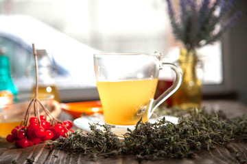 Herbal tea from the viburnum decoction of red sea buckthorn berries and thyme in a transparent glass mug in the village on a wooden table