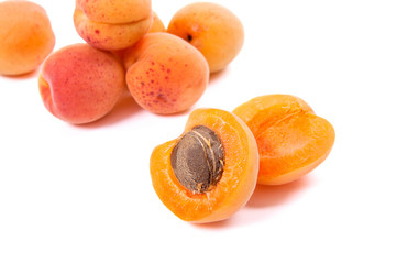 Several of harvested apricots whole and halved on white background..