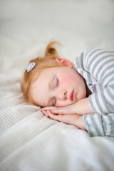 The ruddy girl sleeps with her hands under her cheek