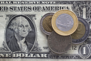 Latin american coins over dollar bill