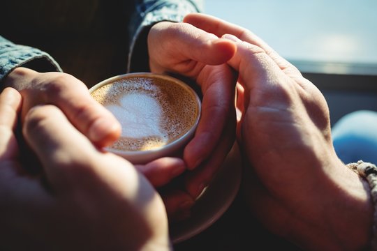 Close-up of man and woman holding coffee cup at cafeteria - Powered by Adobe
