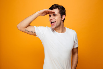 Happy man in t-shirt holding arm on forehead looking away