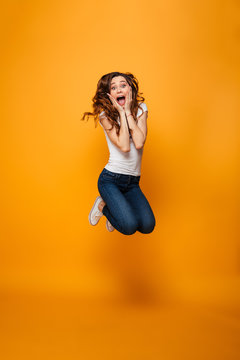 Full length image of Surprised brunette woman in t-shirt jumping