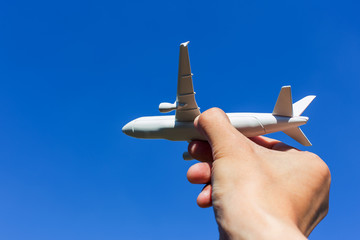 Airplane model in hand on sunny sky. Concepts of travel, transportation, transport, dreaming about holidays