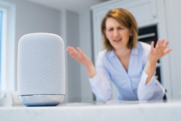 Frustrated Woman In Kitchen Asking Digital Assistant Question