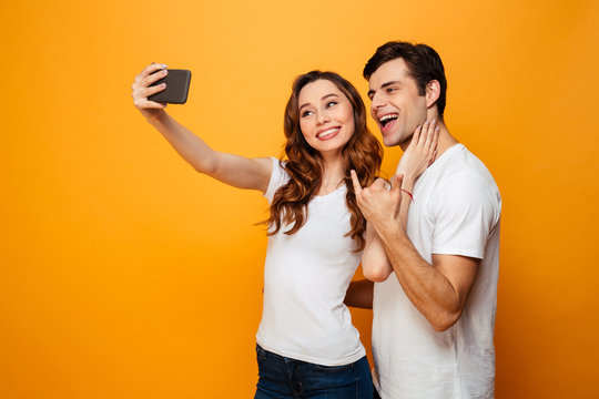 Happy young lovely couple posing together while making selfie