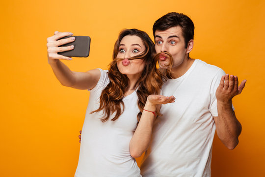 Funny young lovely couple having fun together while making selfie