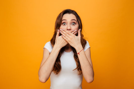 Surprised worried brunette woman in t-shirt covering her mouth