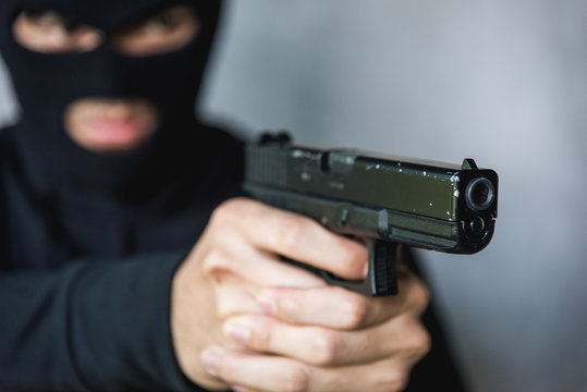 Terrorist or Burglar in black mask shooting the gun aiming