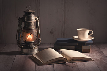 Old, antique book opened and burning kerosene lamp