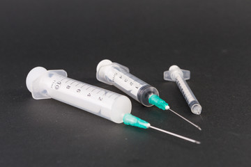 Three plastic disposable syringes on dark background