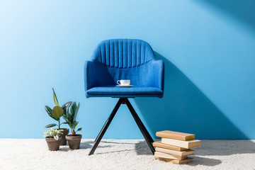 comfy blue armchair with cup of coffee in front of blue wall