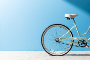 Fototapeta premium back wheel of bicycle standing on carpet in front of blue wall