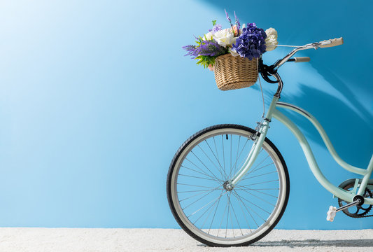 front wheel of bicycle with flowers in basket in front of blue wall