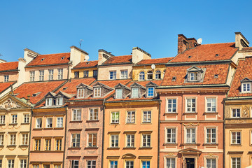 Fototapeta na wymiar Facades of houses with windows and roofs against the blue sky on a clear sunny day in the old town in Warsaw, Poland