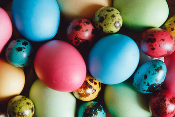 Easter background. Colored eggs of chicken and quail lie in a wicker basket.