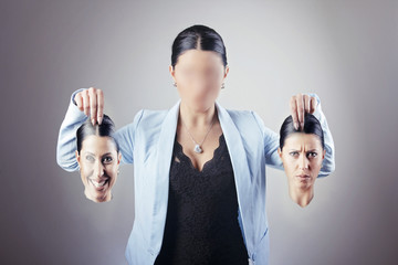 Young business woman choosing her identity for a blank face, holding a happy face and a sad face,...