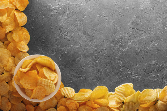 Pile of crispy potato chips lying  on an old concrete table in kitchen. Concept of fast food background. Free place for text, top view.