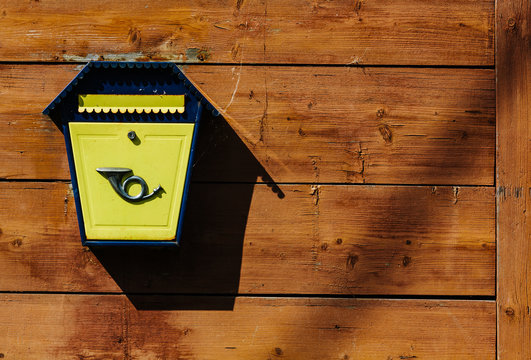 Yellow metal mailbox on a wooden wall