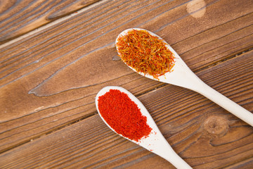 Plastic spoons with dry spices and fresh herbs on a wooden rough boards background, top view, close up