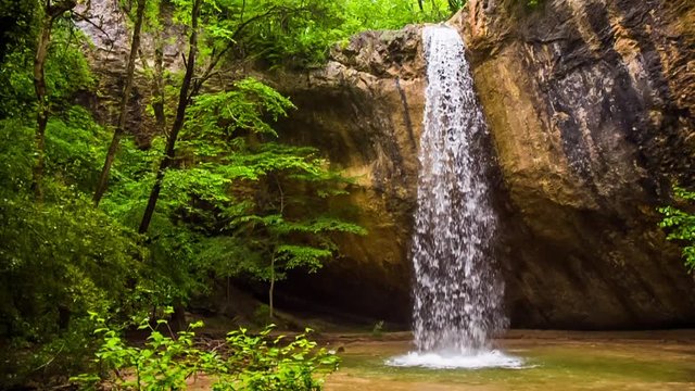 waterfall and cave in the forest. Slow motion.