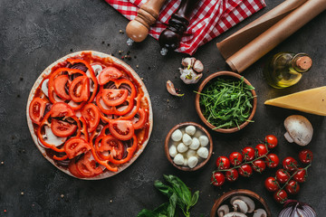 top view of uncooked pizza with various ingredients on concrete table