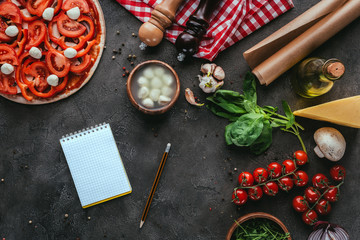 top view of uncooked pizza with notebook on concrete table