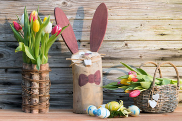 Selbstgemachter Osterhase aus Holz mit Ostereier und Tulpen für das Osterfest