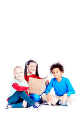 Three multi-ethnic elementary students sitting on floor and reading a book together