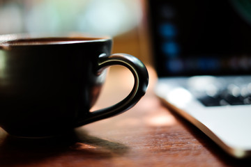 Mockup image of laptop with coffee cup on table in nature outdoor cafe.Select focus cup coffee blurred background.