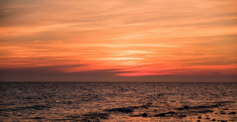 Beautiful colorful sunrise at the sea with clouds in the red sky.