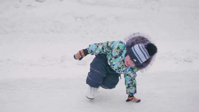 The first steps of a young child on skates. Boy on skates fell and could not rise. Active lifestyle