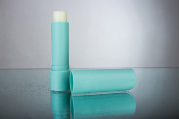 Mint lip balm with on mirror with reflection on grey background