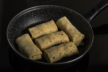 Pancakes stuffed in a frying pan on an induction cooker