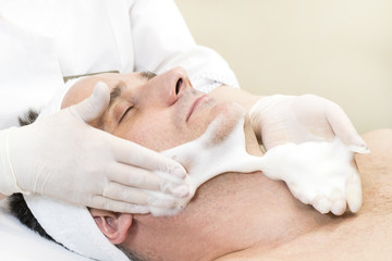 Fototapeta na wymiar Man in the mask cosmetic procedure in spa salon. 